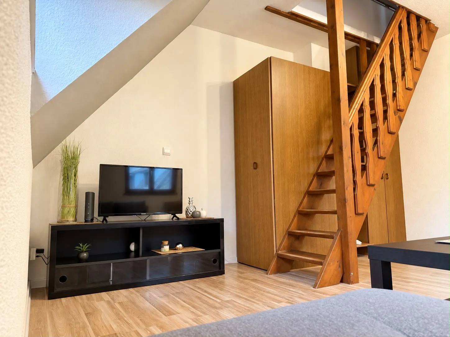 Espace télévision et escalier en bois menant à la mezzanine